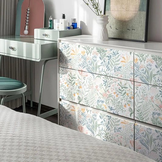 Kommode mit Türen, die mit selbstklebender Tapete mit Blumenmuster beklebt sind, neben einem Frisiertisch