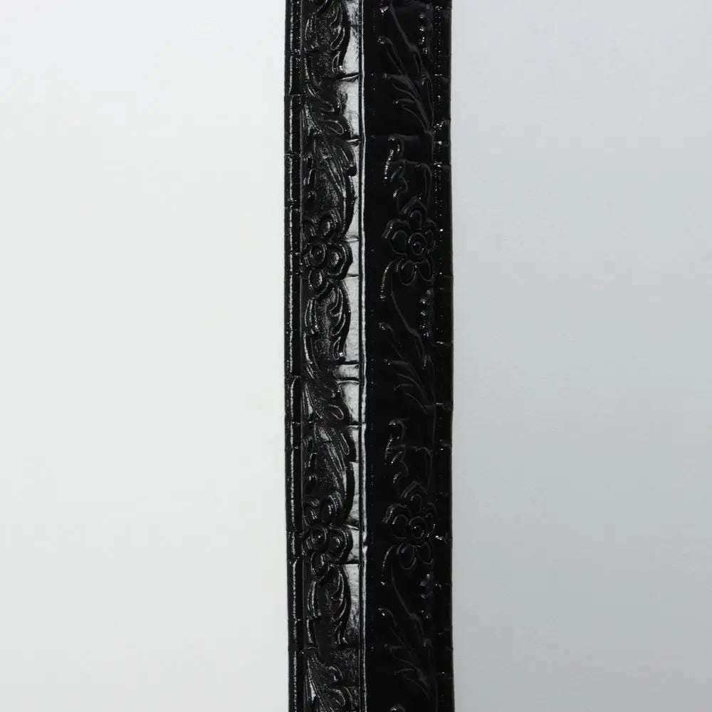 Schwarze Leiste mit Blumenrelief, aufrecht an eine helle Wand gestellt