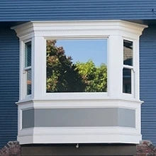 Erker van een huis met spiegelglas dat de lucht en de bomen weerspiegelt