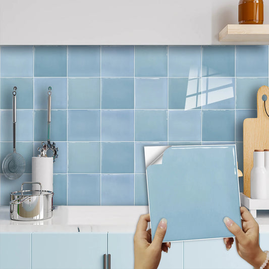 Light blue square sticker with the back paper half peeled, in front of a wall of blue squares