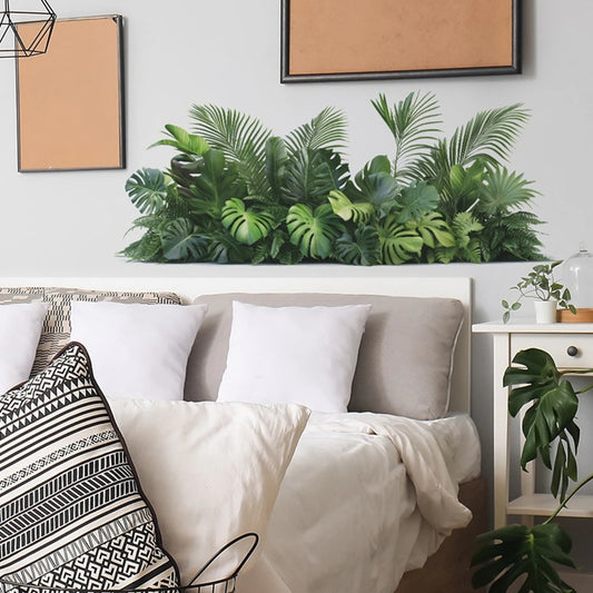 Muursticker met monstera- en palmbladeren boven een bedhoofdbord
