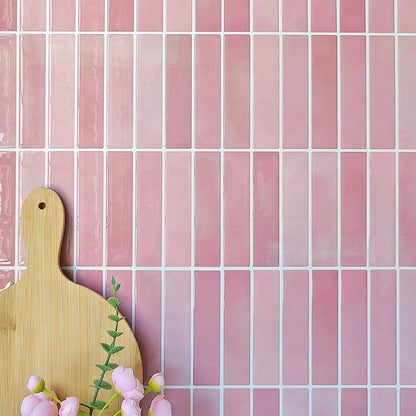 Pink wall with rectangular tile stickers, a wooden chopping board and some flowers