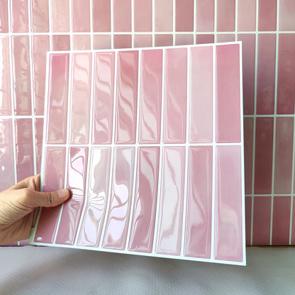 Hand holding a glossy pink tile sticker sheet in front of a tiled wall