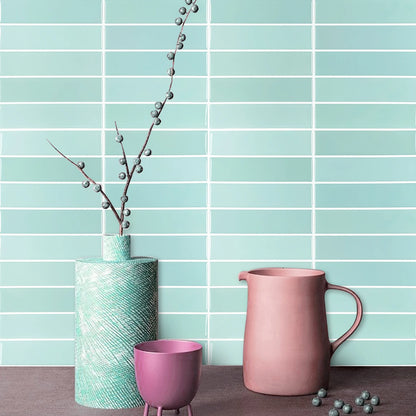 Light blue wall with rectangular tile stickers, a vase, a pink jug and a purple glass
