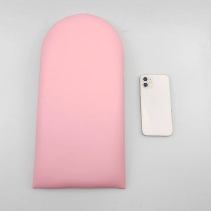 Roze gestoffeerd paneel met een boogvormige bovenrand op een grijze achtergrond, naast een telefoon als maatvergelijking