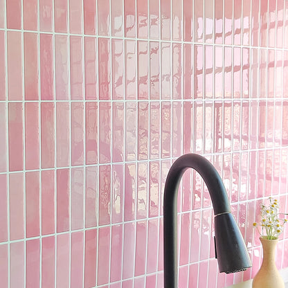 Pink wall with rectangular tile stickers behind a black sink tap