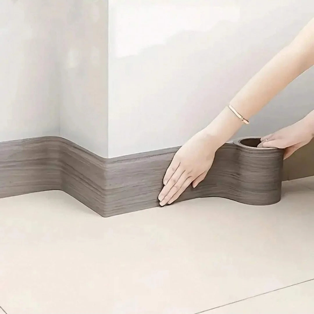 Grey wood effect adhesive strip fitted as a skirting board at the base of a white wall