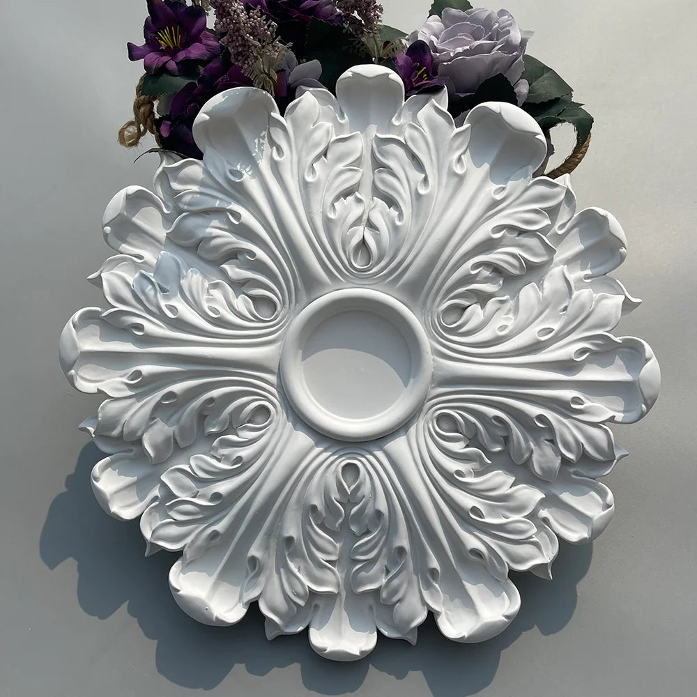 White ceiling rose with leaf relief seen from above, with purple flowers at the top