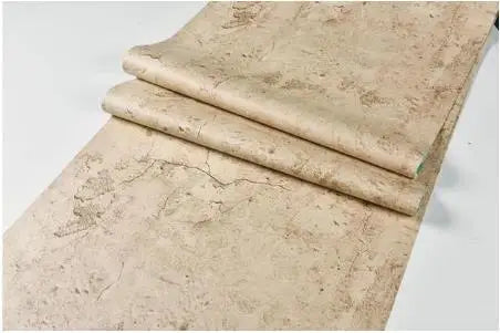 Kaksi retrokeltaista betonin näköistä itseliimautuvaa tapettirullaa, hiekanbeige, valkoisella taustalla