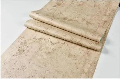Kaksi retrokeltaista betonin näköistä itseliimautuvaa tapettirullaa, hiekanbeige, valkoisella taustalla