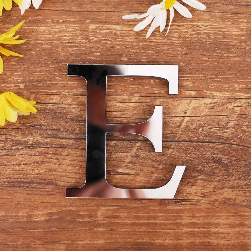 Letter E in silver mirror acrylic, 20 cm, on a wooden table with flowers