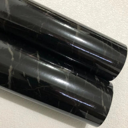 Zwei Rollen glänzende schwarze Klebefolie in Marmoroptik mit hellen Adern