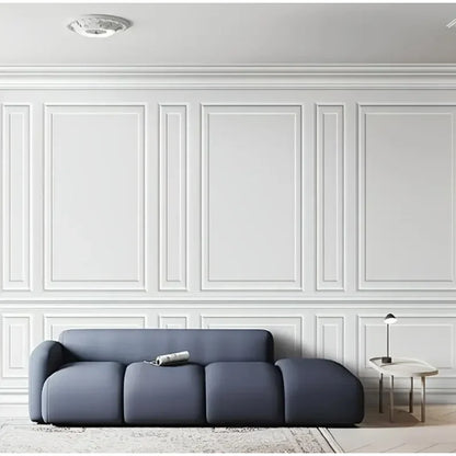 Woonkamer met een bank en muren versierd met witte verhoogde lijsten