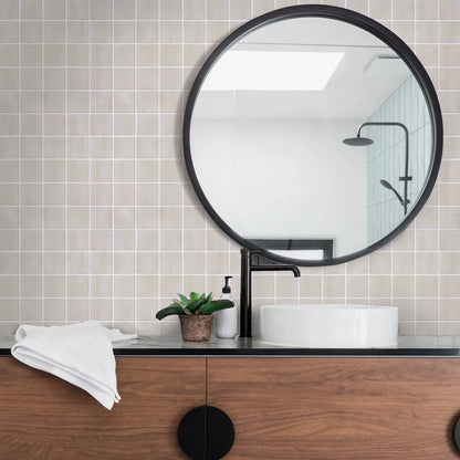 Bathroom wall, behind the mirror and washbasin, covered in beige square panels