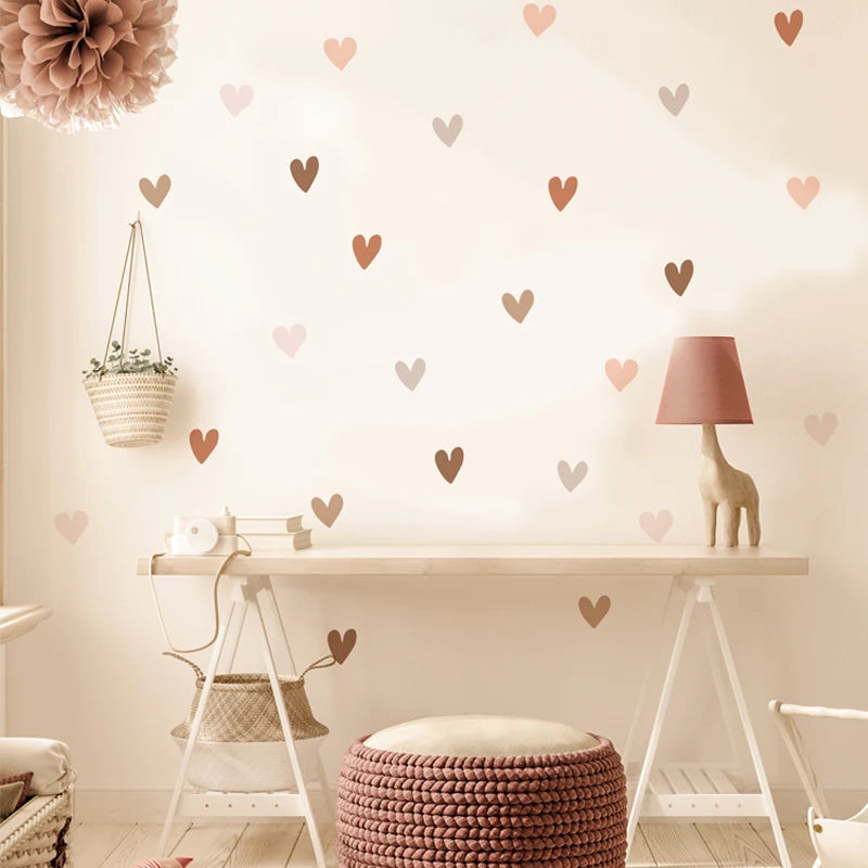 Pink wall with heart stickers spread over a desk with a giraffe-shaped lamp