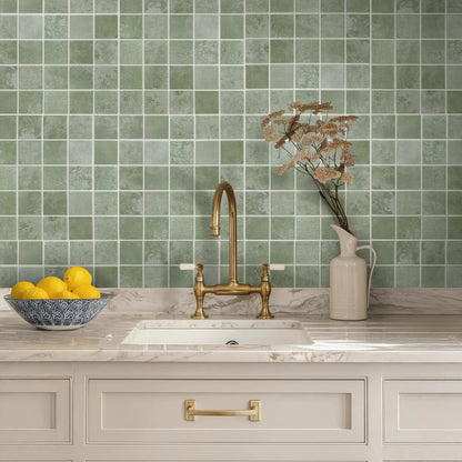 Wall behind a kitchen sink covered in mint green square panels