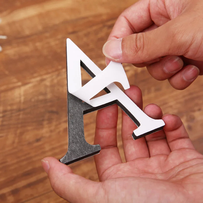 Hands removing the film from a mirror effect letter A with a black foam base