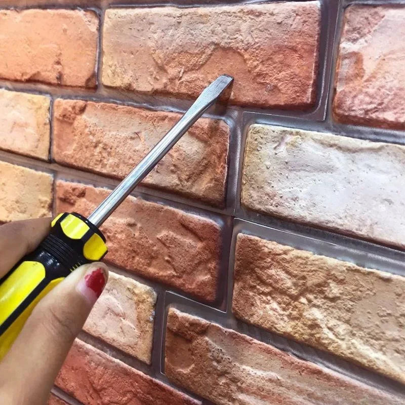 Close-up of raised red brick effect panels with dark joints and a screwdriver