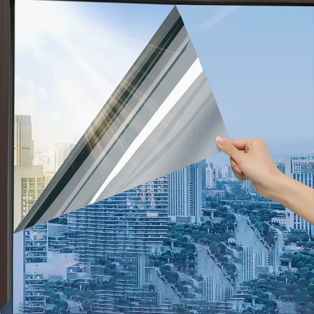 Hand die een hoek van spiegelfolie losmaakt van een raam met uitzicht op de stad