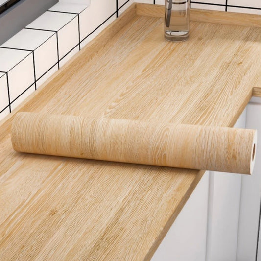 Roll of honey yellow wood effect adhesive vinyl on a covered worktop, in front of white tiles