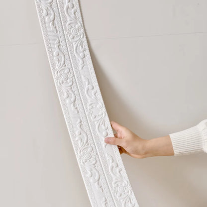A hand rests the white raised moulding against a light wall