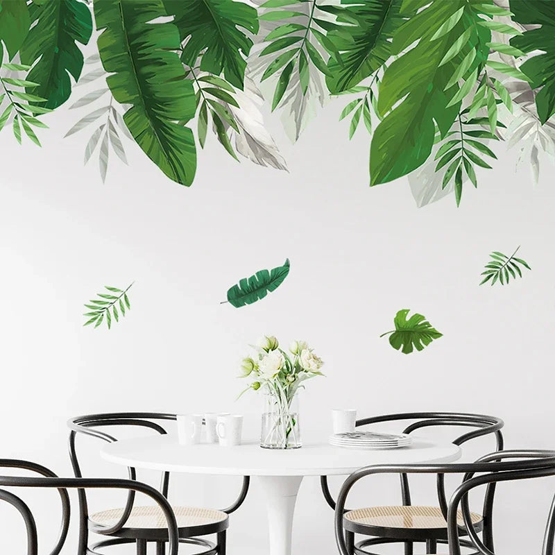 Strook groene tropische bladeren op de wand boven een ronde tafel met zwarte stoelen