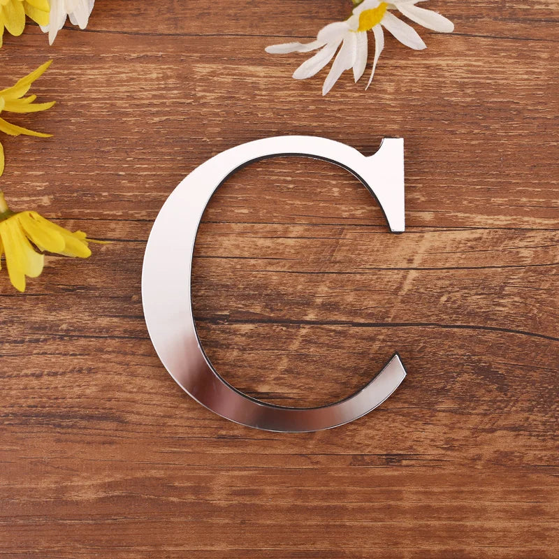 Letter C in silver mirror acrylic, 20 cm, on a wooden table with flowers