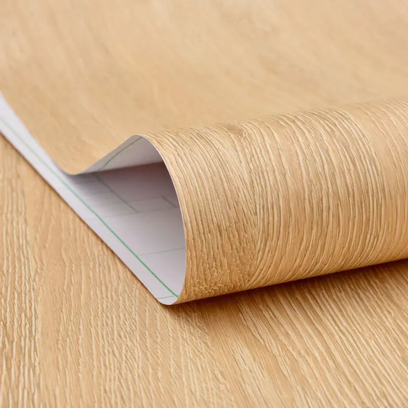 Roll of wood effect vinyl wrap partly unrolled, with the white back visible