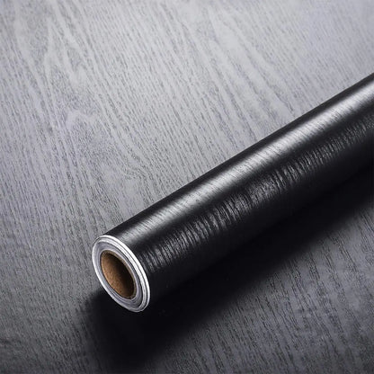 Roll of black wood effect vinyl wrap, Model 2, on a dark wood background