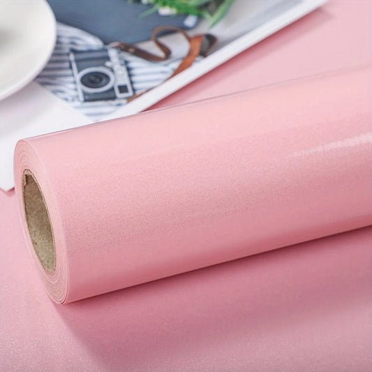 Nahaufnahme einer Rolle glänzender rosa selbstklebender Tapete, mit einer Kamera im Hintergrund