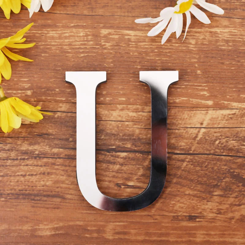 Letter U in silver mirror acrylic, 20 cm, on a wooden table with flowers