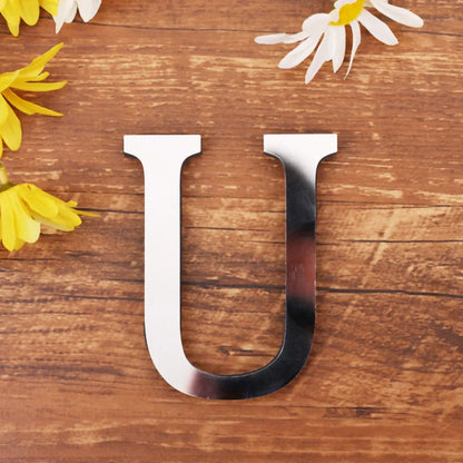 Letter U in silver mirror acrylic, 20 cm, on a wooden table with flowers