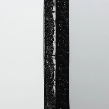 Schwarze Leiste mit Blumenrelief, aufrecht an eine helle Wand gestellt