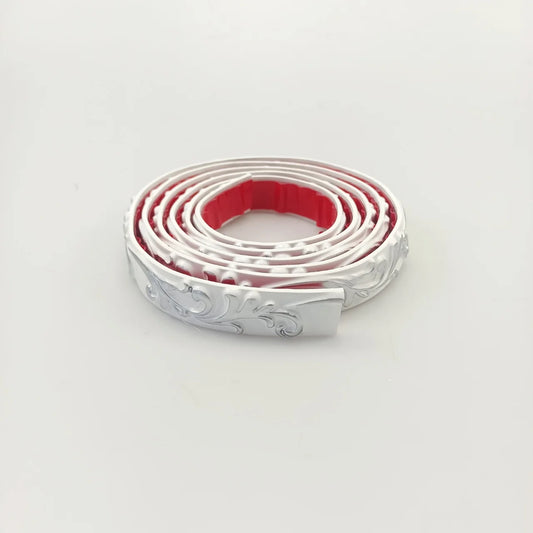 White decorative moulding with silver decoration, rolled up, with the red adhesive back visible