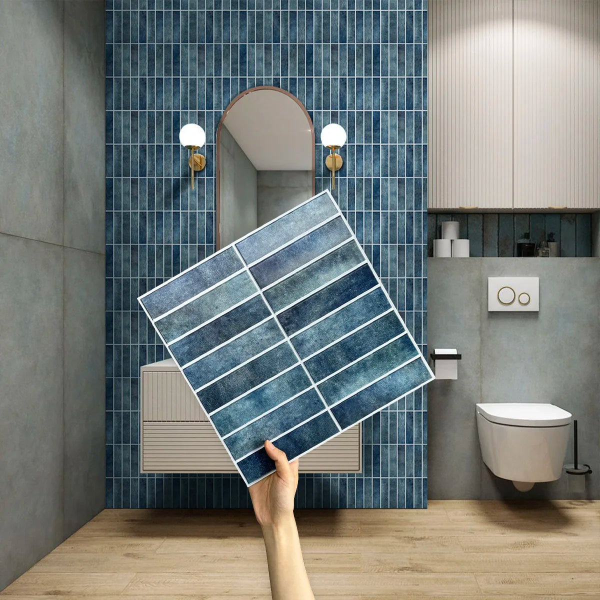 A hand holds a blue strip sheet in front of a bathroom wall with wall-hung toilet