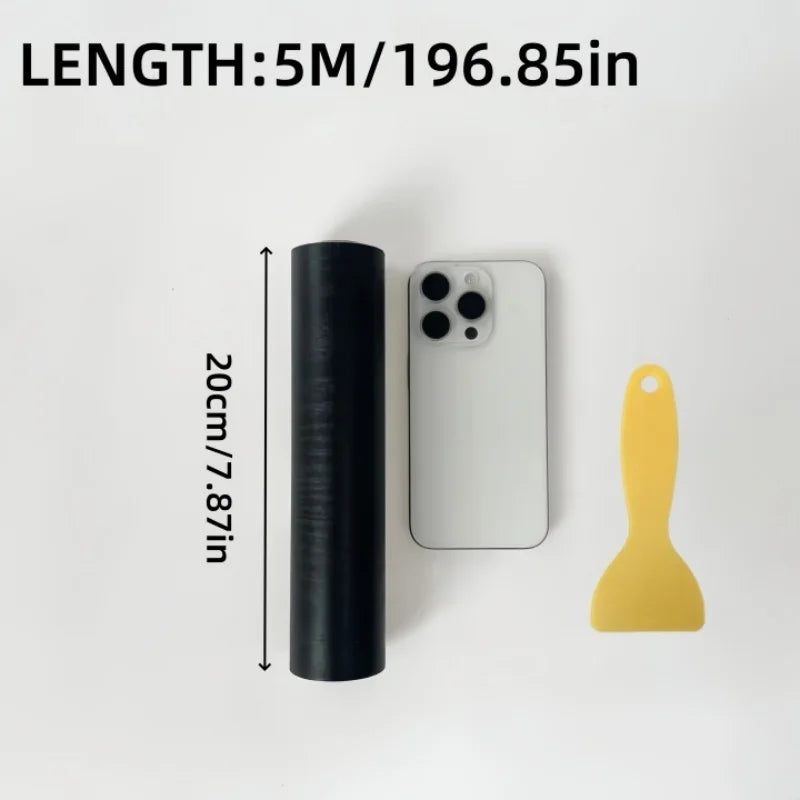 Rulla mustaa puukuvioista tarralistaa, 20 cm leveä, matkapuhelimen ja lastan vieressä
