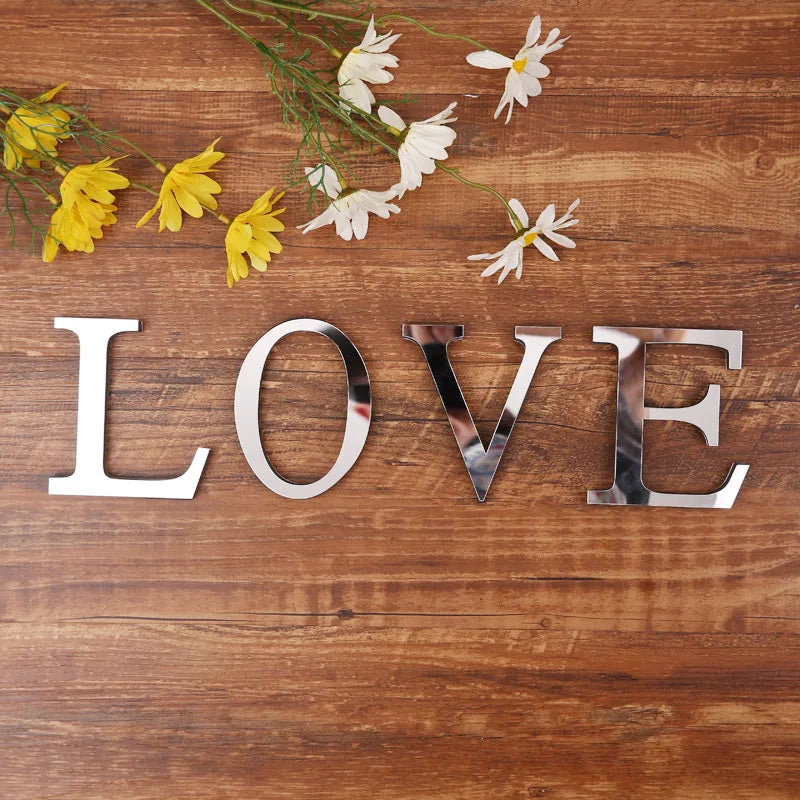 Word LOVE spelled with silver mirror letters on a wooden table