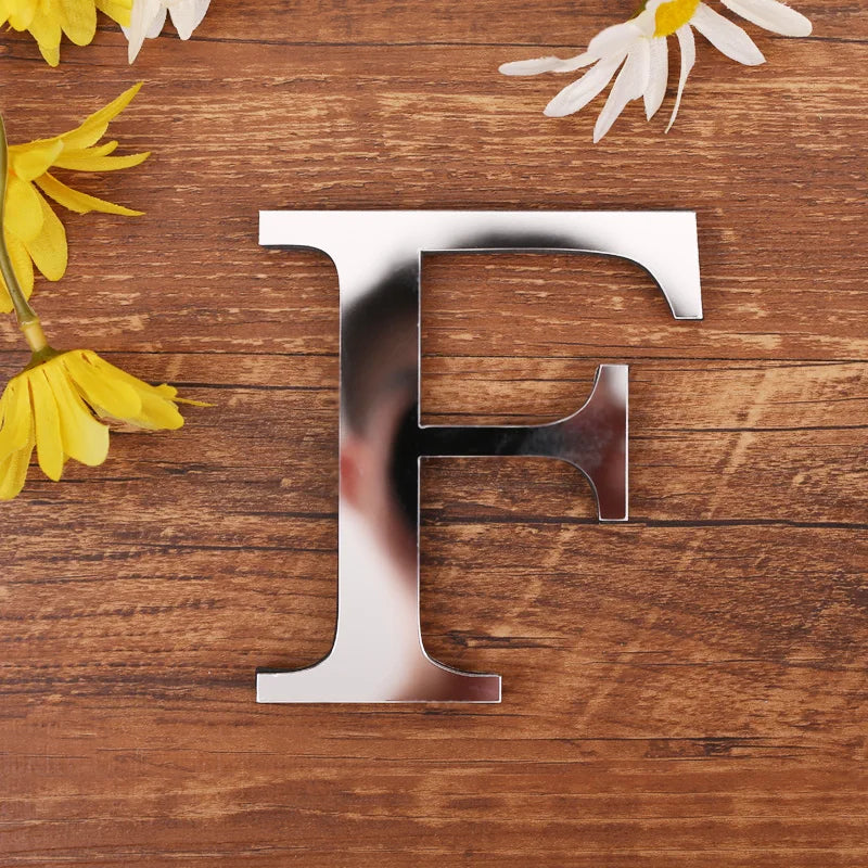 Letter F in silver mirror acrylic, 20 cm, on a wooden table with flowers