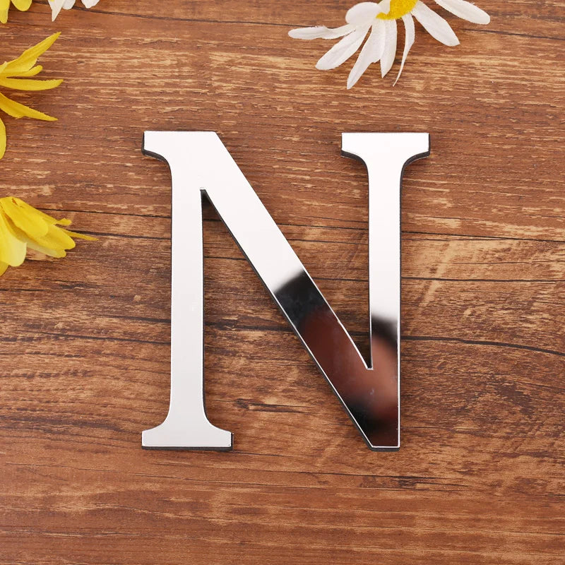 Letter N in silver mirror acrylic, 20 cm, on a wooden table with flowers