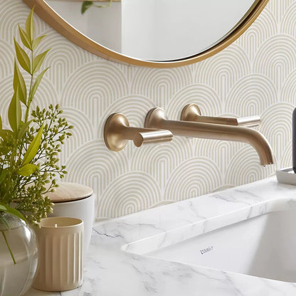 Bathroom wall covered with cream arch stickers, gold tap, round mirror and plants