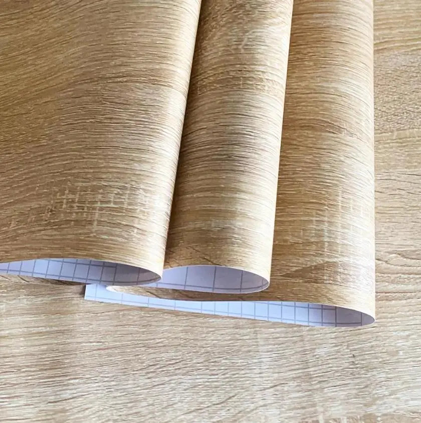 Zwei Rollen Klebefolie in Holzoptik mit rasterbedrucktem Schutzpapier auf der Rückseite