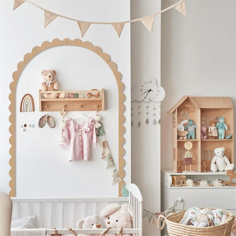 Decoratieve boog met schulprand rond een plank met kinderkleding in een kinderkamer