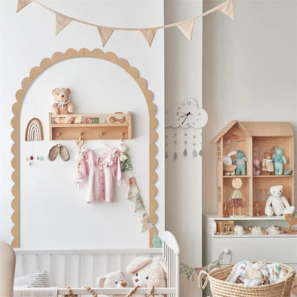Decoratieve boog met schulprand rond een plank met kinderkleding in een kinderkamer