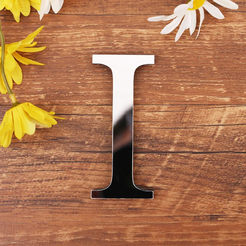 Letter I in silver mirror acrylic, 20 cm, on a wooden table with flowers