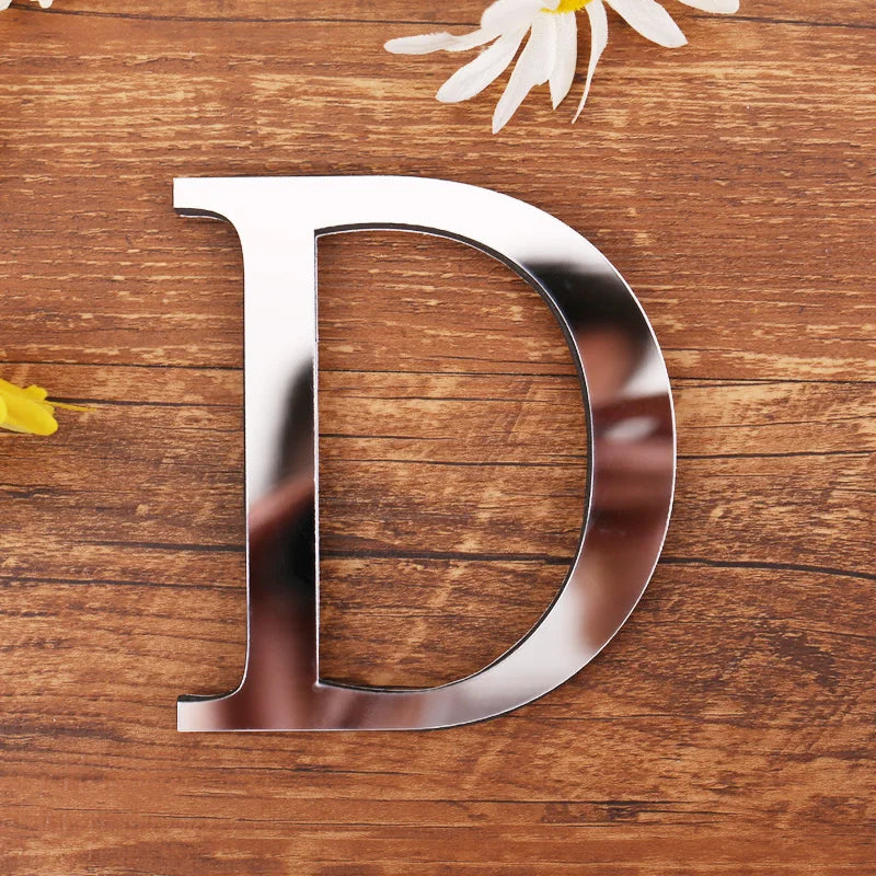 Letter D in silver mirror acrylic, 20 cm, on a wooden table with flowers