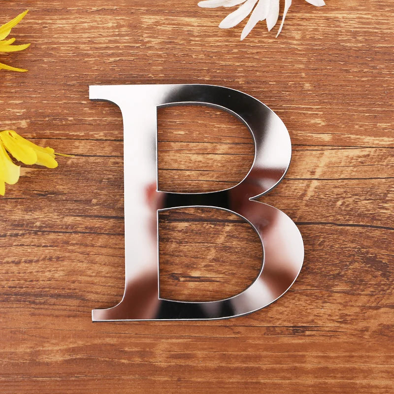Letter B in silver mirror acrylic, 20 cm, on a wooden table with flowers