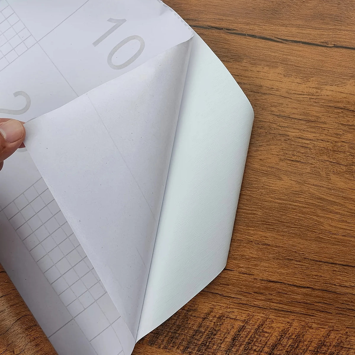 Paperin irrottaminen puukuvioisen tarrakalvon takapuolelta