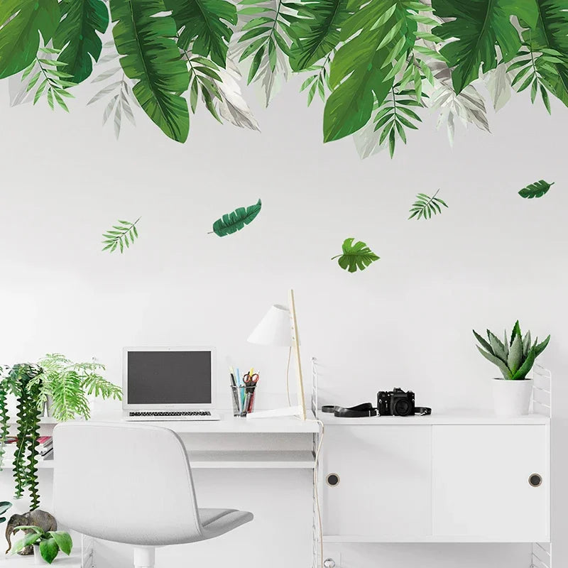 Strook groene tropische bladeren op de wand boven een wit bureau met een computer