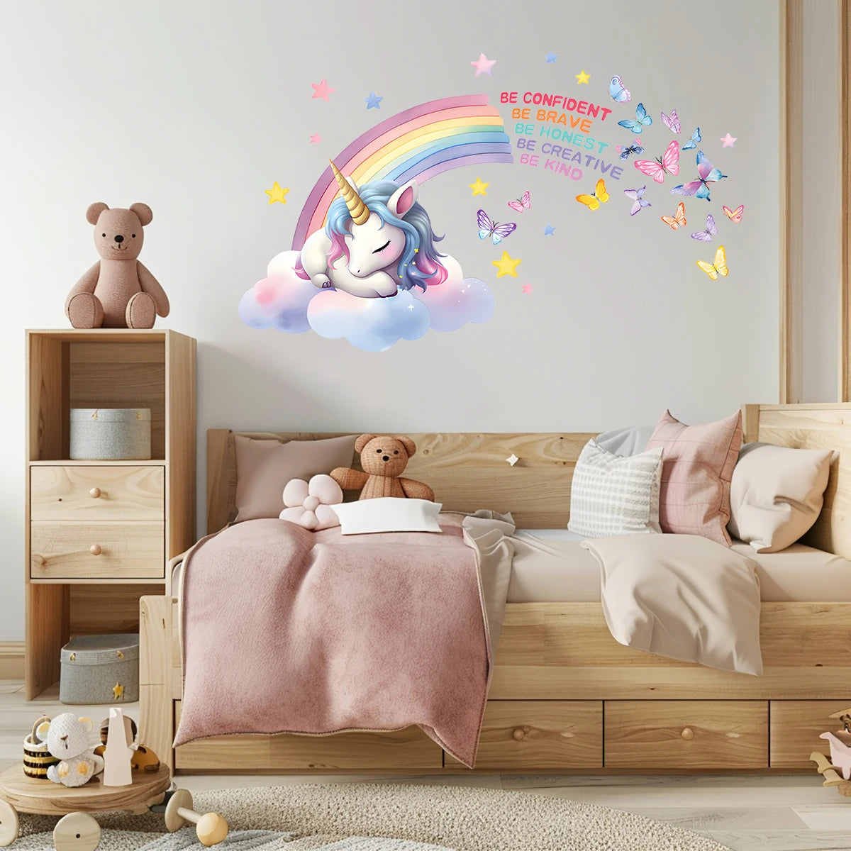 Kinderkamer met een roze bed, een teddybeer en de muursticker met eenhoorn en regenboog