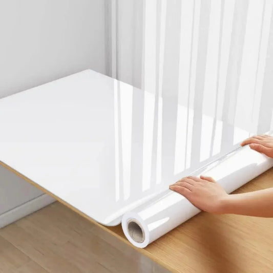 Roll of glossy white adhesive vinyl unrolled on a wooden board